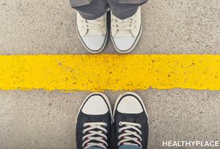 Stock image of two people's shoes facing each other separated by yellow lines. 